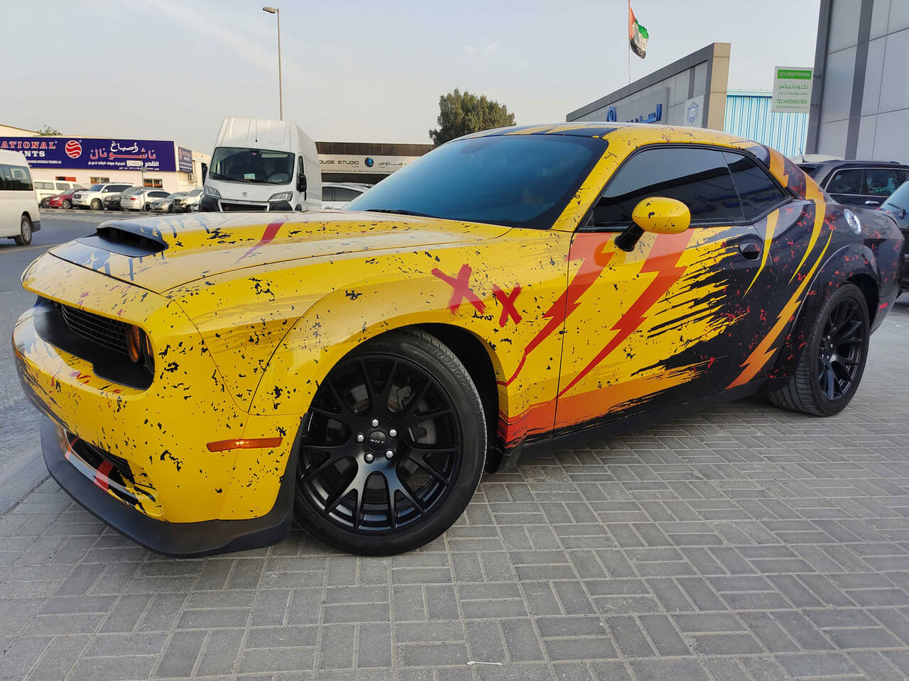 Yellow Dodge Challenger car wrap with black splatter and lightning graphics, Dubai.